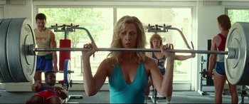 Movie still from “Wonder Woman 1984” (2020), directed by Patty Jenkins – A woman in a blue top is lifting a barbell; Medium shot, Low angle