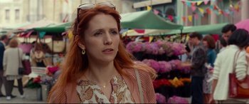 Movie still from “Wonder Woman 1984” (2020), directed by Patty Jenkins – A woman with red hair is standing in front of flowers; Close Up shot, Over the shoulder angle