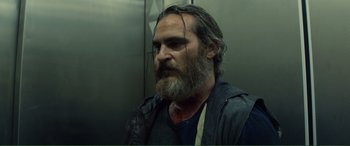 A man with long hair and a beard is standing in an elevator