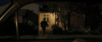 Movie still from “Zodiac” (2007), directed by David Fincher – A person walking down the sidewalk of a house; Wide shot, Low angle