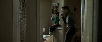 Movie still from “Zodiac” (2007), directed by David Fincher – A man sitting on the edge of a bathroom sink; Wide shot, Over the shoulder angle
