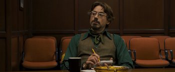 Movie still from “Zodiac” (2007), directed by David Fincher – A man sitting at a table with a cup of coffee; Medium shot, Over the shoulder angle