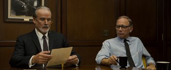 Movie still from “Zodiac” (2007), directed by David Fincher – Two men are sitting at a table and one of the men is holding papers; Medium shot, Over the shoulder angle