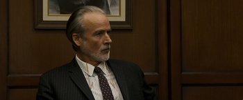 Movie still from “Zodiac” (2007), directed by David Fincher – An older man in a suit and tie looking to his left; Close Up shot, Over the shoulder angle