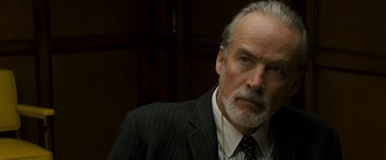 Movie still from “Zodiac” (2007), directed by David Fincher – An older man in a suit with a beard; Close Up shot, Over the shoulder angle