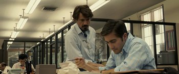 Movie still from “Zodiac” (2007), directed by David Fincher – Two men working together in an office setting; Medium shot, Over the shoulder angle