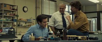 Movie still from “Zodiac” (2007), directed by David Fincher – Three men are standing around a table and one man is sitting at a desk; Medium shot, Low angle