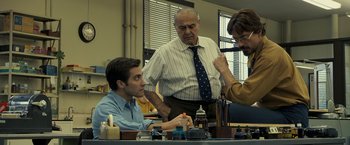 Movie still from “Zodiac” (2007), directed by David Fincher – A group of men standing around a table; Medium shot, Low angle