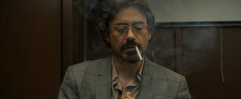 Movie still from “Zodiac” (2007), directed by David Fincher – A person wearing glasses and smoking a cigarette; Close Up shot, Over the shoulder angle