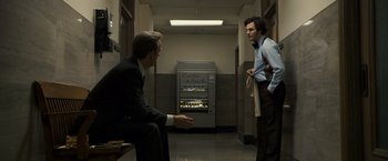 Movie still from “Zodiac” (2007), directed by David Fincher – Two men in suits are standing in a hallway; Medium shot, Low angle