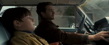 Movie still from “Zodiac” (2007), directed by David Fincher – A man and a woman driving a car in the road; Close Up shot, Over the shoulder angle