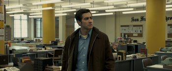A man standing in a room with a book case in front of him