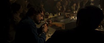 Movie still from “Zodiac” (2007), directed by David Fincher – A man sitting at a table smoking a cigarette; Medium shot, Over the shoulder angle