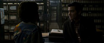 Movie still from “Zodiac” (2007), directed by David Fincher – Two people sitting at a table in front of a bookshelf; Close Up shot, Over the shoulder angle