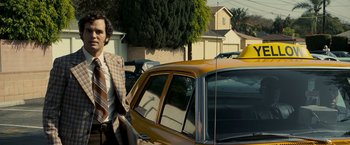 Movie still from “Zodiac” (2007), directed by David Fincher – A man standing next to a yellow taxi cab; Medium shot, Low angle