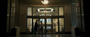 Movie still from “Zodiac” (2007), directed by David Fincher – Two people are walking through a glass door; Extreme Wide shot, Low angle