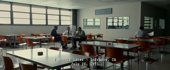 Movie still from “Zodiac” (2007), directed by David Fincher – A group of people sitting at a table in a room; Extreme Wide shot, High angle