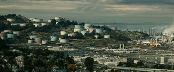 Movie still from “Zodiac” (2007), directed by David Fincher – A view of a city with a bunch of tanks on top of a hill; Extreme Wide shot, High angle