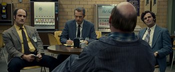 Movie still from “Zodiac” (2007), directed by David Fincher – A man sitting at a table in front of another man; Medium shot, Over the shoulder angle