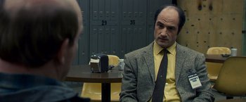 Movie still from “Zodiac” (2007), directed by David Fincher – A man sitting at a table in front of another man; Medium shot, Over the shoulder angle