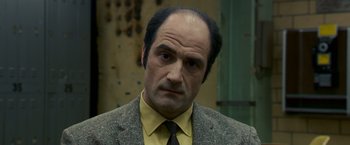 Movie still from “Zodiac” (2007), directed by David Fincher – A man in a suit and tie looking at the camera; Close Up shot, Low angle