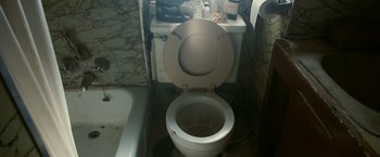 Movie still from “Zodiac” (2007), directed by David Fincher – A bathroom with a toilet , sink , tub , and mirror; Medium shot, Overhead angle