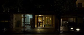 Movie still from “Zodiac” (2007), directed by David Fincher – A man standing in front of a building at night; Extreme Wide shot, Low angle