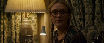 Movie still from “Zodiac” (2007), directed by David Fincher – A woman wearing glasses and braids in front of a lamp; Close Up shot, Over the shoulder angle