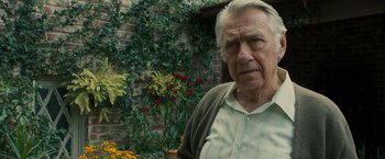 Movie still from “Zodiac” (2007), directed by David Fincher – An older man standing in front of a flower garden; Close Up shot, Over the shoulder angle