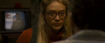 Movie still from “Zodiac” (2007), directed by David Fincher – A woman wearing glasses looking at the camera; Close Up shot, Over the shoulder angle