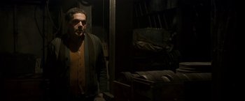 Movie still from “Zodiac” (2007), directed by David Fincher – A man standing in a dark room next to a bunch of boxes; Medium shot, Low angle