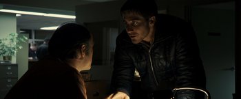 Movie still from “Zodiac” (2007), directed by David Fincher – A man in black jacket talking to another man in black jacket; Medium shot, Over the shoulder angle