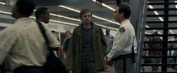 Movie still from “Zodiac” (2007), directed by David Fincher – A man standing next to another man in a crowd of people; Medium shot, Over the shoulder angle