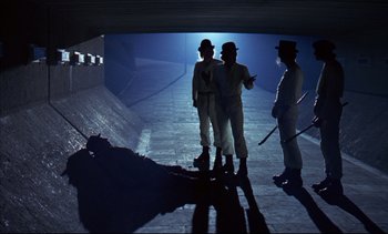 Movie still from “A Clockwork Orange” (1971), directed by Stanley Kubrick – A group of men standing next to each other on a street; Wide shot, Low angle
