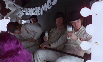 Movie still from “A Clockwork Orange” (1971), directed by Stanley Kubrick – A group of men sitting next to each other holding drinks; Medium shot, High angle