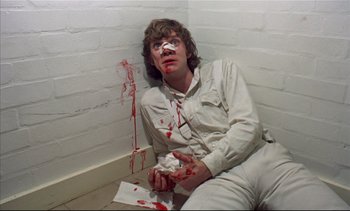 Movie still from “A Clockwork Orange” (1971), directed by Stanley Kubrick – A man sitting on the ground with a piece of paper in front of him; Medium shot, Overhead angle