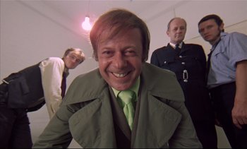 Movie still from “A Clockwork Orange” (1971), directed by Stanley Kubrick – A group of men standing next to each other in a room; Medium shot, Low angle