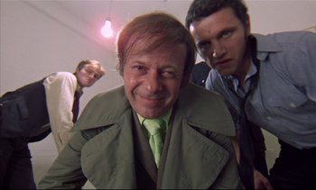 Movie still from “A Clockwork Orange” (1971), directed by Stanley Kubrick – A group of men standing next to each other in a room; Medium shot, Low angle