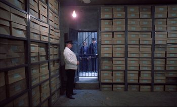 Movie still from “A Clockwork Orange” (1971), directed by Stanley Kubrick – A man standing in front of boxes in a room; Wide shot, High angle