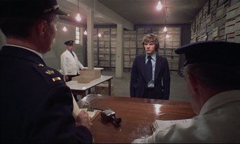 Movie still from “A Clockwork Orange” (1971), directed by Stanley Kubrick – A man in a suit standing in front of two other men; Medium shot, Over the shoulder angle