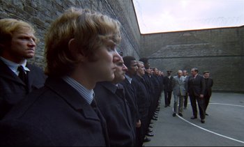 Movie still from “A Clockwork Orange” (1971), directed by Stanley Kubrick – A group of men in suits standing in a line; Wide shot, High angle