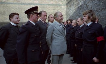 Movie still from “A Clockwork Orange” (1971), directed by Stanley Kubrick – A group of men standing next to each other in suits; Medium shot, Over the shoulder angle
