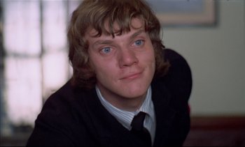 Movie still from “A Clockwork Orange” (1971), directed by Stanley Kubrick – A man with long blonde hair wearing a suit and tie; Close Up shot, Low angle