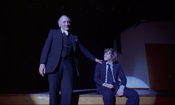 Movie still from “A Clockwork Orange” (1971), directed by Stanley Kubrick – Two men in suits and ties on a stage; Medium shot, Low angle
