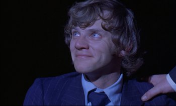 Movie still from “A Clockwork Orange” (1971), directed by Stanley Kubrick – A man in a suit and tie looking up at the sky; Close Up shot, Low angle
