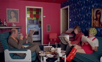 Movie still from “A Clockwork Orange” (1971), directed by Stanley Kubrick – Two people are sitting in a living room reading newspapers; Wide shot, High angle