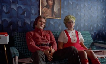 Movie still from “A Clockwork Orange” (1971), directed by Stanley Kubrick – A man and a woman sitting on a blue couch; Medium shot, High angle