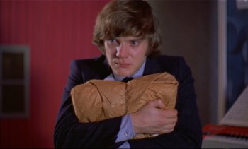 Movie still from “A Clockwork Orange” (1971), directed by Stanley Kubrick – A man holding a brown paper bag in front of his face; Close Up shot, Low angle
