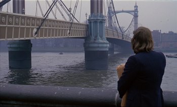 Movie still from “A Clockwork Orange” (1971), directed by Stanley Kubrick – A person standing in front of a bridge; Extreme Wide shot, Over the shoulder angle