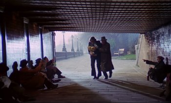 Movie still from “A Clockwork Orange” (1971), directed by Stanley Kubrick – A couple of people that are standing under a bridge; Wide shot, High angle